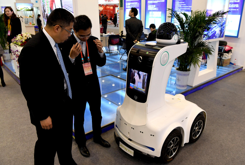 3月29日，参会展商在向客商介绍一款小区智能安保机器人产品。